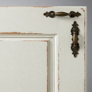 Detailed view of an antique white kitchen cabinet door, highlighting its subtle texture and classic hardware.