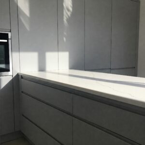 Modern gray kitchen cabinets complemented by a bright quartz countertop.