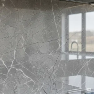 Close-up view of a polished grey marble kitchen backsplash, showcasing its natural veining and elegant finish.