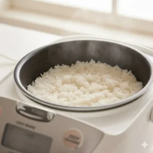 Freshly cooked fluffy white rice inside the non-stick pot of a steamer rice cooker.