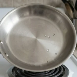 Small water droplets dancing on a hot surface, a key technique in how to preheat pan correctly for cooking.