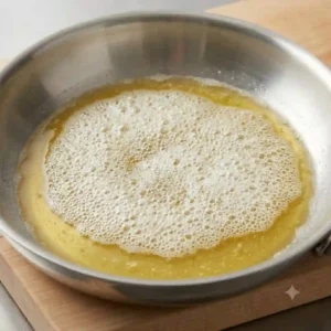 Butter melting and foaming perfectly in a pan, providing a visual cue for how to cook with butter without burning.
